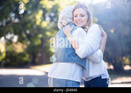 Aufrichtige junge Frau umarmt alte Mutter Natur Stockfoto