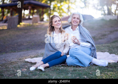 Lächelnde Frau genießen Dessert mit alte Mutter im park Stockfoto