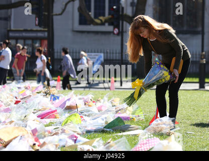 Eine Frau fährt einige Blumen floral Tribute in Parliament Square außerhalb des Palace of Westminster, wo der Terroranschlag in London stattfand. Stockfoto