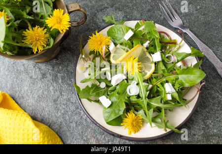 Löwenzahn-Salat mit Zwiebeln und Käse auf einem Teller Stockfoto
