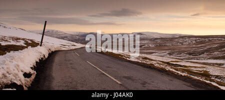 2-spurige Buttertubs Pass windet sich die Straße über verschneite Mauren nach unten in Richtung Hawes und Wensleydale in Yorkshire Dales Englands im Winter. Stockfoto