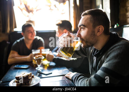 Mann Bier trinken an zu trinken Freunde im Pub zu diskutieren. Stockfoto