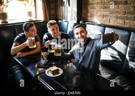 Schöne Freunde trinken Bier, tun Selfie und lächelnd beim Ausruhen im pub Stockfoto