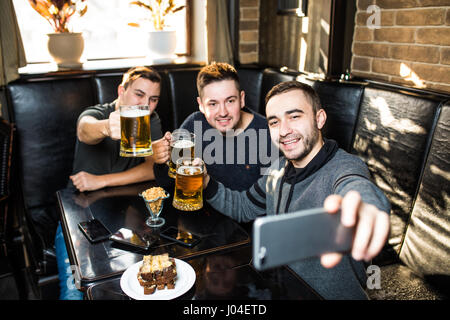 Schöne Freunde trinken Bier, tun Selfie und lächelnd beim Ausruhen im pub Stockfoto