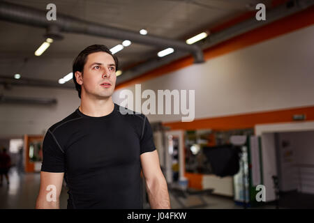 Lebensstil-Porträt von schönen muskulösen Mann im schwarzen T-shirt Standing in der Sporthalle. Stockfoto