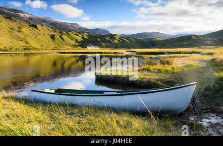 Eine traditionelle Woden Ruderboot liegt am Ufer eines kleinen See oder man, im Tal von Glen Torridon, unter den Torridon Hills Bergen in Stockfoto