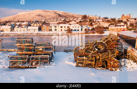 Hummer-Töpfe liegen unter den unberührten Schnee auf dem Deich von Helmsdale Hafen an der Moray Firth von Sutherland in den Highlands von Schottland. Stockfoto