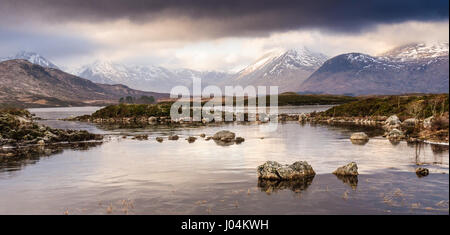 Winter-Eis überzieht man Na h-Achlaise See auf der großen Torfmoor Heide von Rannoch Moor, mit schneebedeckten schwarzen Berge in der Ferne. Stockfoto