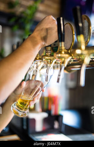 Mans Hand strömenden Pint Bier hinter der bar Stockfoto