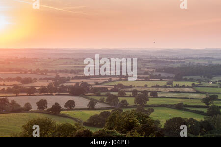 Die Sonne über einem Flickenteppich aus Weide, Felder, Feldfrüchte und Wäldern im Blackmore vale Landwirtschaft Stadtteil North Dorset, aus bulbarrow Hill gesehen Stockfoto