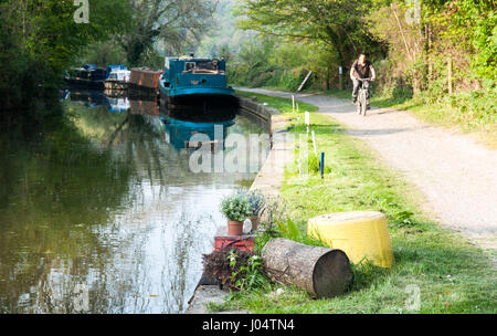 Bath, England - 19. April 2011: Ein Radfahrer, der vorbeifahrenden Boote auf dem Treidelpfad Kennet & Avon Canal in der Nähe von Bath in Somerset. Stockfoto