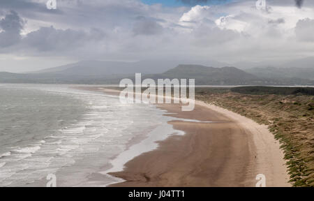 MOEL-y-Gest und andere Berge des Snowdonia National Park steigen hinter dem langen Strand und Sand Dune-System bei Morfa Harlech in Nord-Wales. Stockfoto