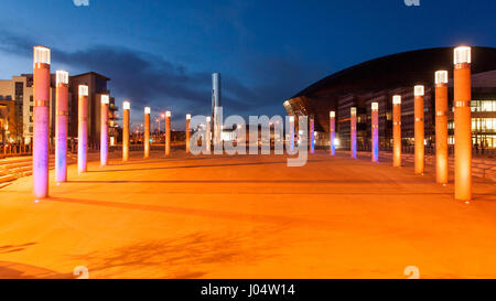 Cardiff, Wales, UK - 17. März 2013: Roald Dahl Plass in Cardiff Bay ist von bunten bildhauerischen Lichter in der Nacht, mit das Wales Millennium Centre beleuchtet Stockfoto