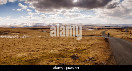 Ein einsamer Radfahrer überquert die Fernbedienung aber sonnigen Sunbiggin Moors, in Richtung der schneebedeckten Berge des Howgill Fells in Eden District von Cumbria. Stockfoto