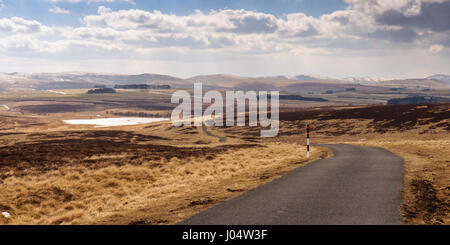 Einspurigen Landstraße überquert die offenen Moorlandschaften von Sunbiggin Moore, mit der Howgill Berge in der Ferne in Cumbria, England. Stockfoto