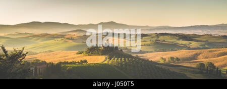 Klassische Ansicht der malerischen toskanischen Landschaft mit berühmten Bauernhaus inmitten von idyllischen Hügeln und Tälern im schönen goldenen Morgenlicht bei Sonnenaufgang Stockfoto