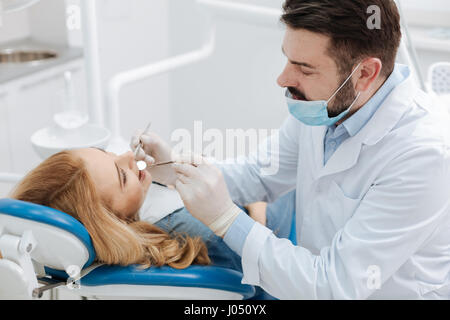 Geschickte schöne Zahnarzt sehr vorsichtig zu sein Stockfoto