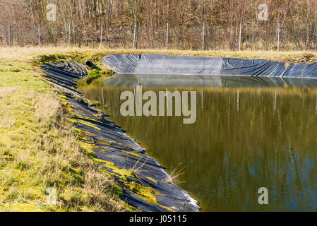 Deponie Sickerwasser Gießen in Teich aus einem schwarzen Rohr. Ort Ronneby, Schweden. Stockfoto