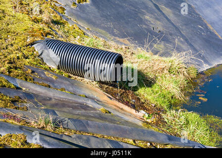 Deponie Sickerwasser Gießen in Teich aus einem schwarzen Rohr. Ort Ronneby, Schweden. Stockfoto