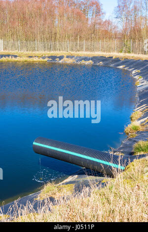 Deponie Sickerwasser Gießen in Teich aus einem schwarzen und blauen Rohr. Ort Ronneby, Schweden. Stockfoto