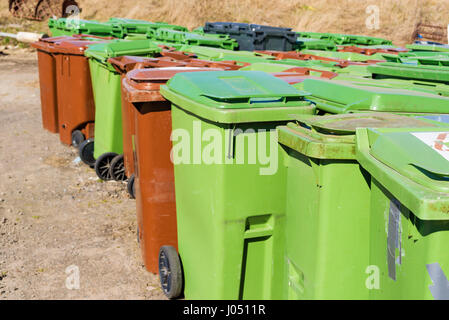 Ausrangierte grüne und braune Mülltonnen gespeichert im Freien warten recycelt werden. Logos entfernt. Stockfoto