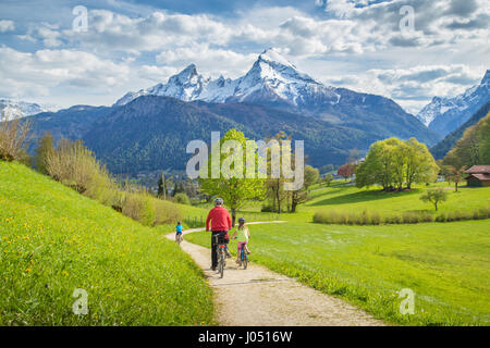 Schöne Aussicht auf eine Gruppe von Bikern, Radfahren auf einem malerischen Weg in idyllischer Bergkulisse der Alpen mit frischen grünen Wiesen an einem sonnigen Tag im Frühling Stockfoto