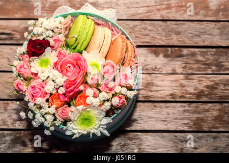 Box mit Rose, verschiedene Blumen und süßen Macarons als romantisches Geschenk Stockfoto
