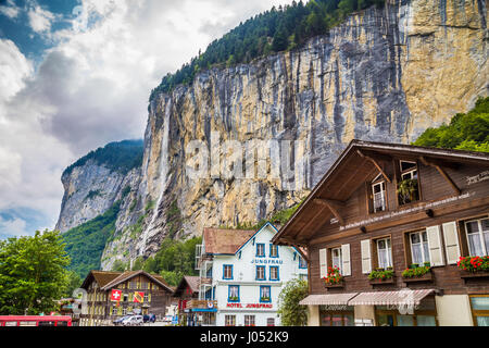 Schöne Aussicht auf die historische Stadt Lauterbrunnen mit berühmten Staubbachfall im Hintergrund an einem sonnigen Tag mit Wolken im Sommer, Schweiz Stockfoto