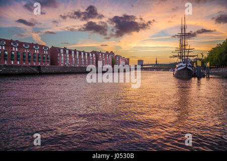 Panoramablick auf die Altstadt von Bremen mit einem alten Segelschiff an Weser im schönen goldenen Abendlicht bei Sonnenuntergang im Sommer Stockfoto