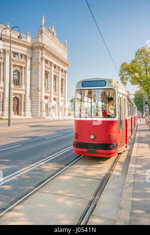 Klassische Ansicht der berühmten Wiener Ringstraße mit historischen Burgtheater (Imperial Court Theatre) und traditionelle rote elektrische Straßenbahn auf einen schönen sonnigen da Stockfoto