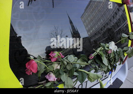 Scheibenwischer eines schwedischen Polizei (Polis) Auto mit Blumen, außerhalb geparkt Ahlens hat City T-Centralen metro station mit Reflexionen der Kirche der Hl. Klara oder Santa Klara Kyrka (Klara Kirche) auf der Oberfläche der Windschutzscheibe, die Umgebung in der Nähe des Stockholmer Terroranschlag. Blick von Ahlens hat Mall. Die Stadt Stockholm, Schweden. 9. April 2017. Stockfoto