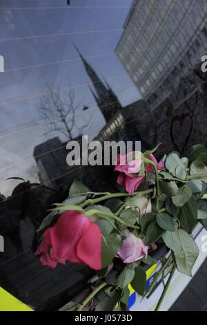 Scheibenwischer eines schwedischen Polizei (Polis) Auto mit Blumen, außerhalb geparkt Ahlens hat City T-Centralen metro station mit Reflexionen der Kirche der Hl. Klara oder Santa Klara Kyrka (Klara Kirche) auf der Oberfläche der Windschutzscheibe, die Umgebung in der Nähe des Stockholmer Terroranschlag. Blick von Ahlens hat Mall (Stockholm City Metro Station). Die Stadt Stockholm, Schweden. 9. April 2017. Stockfoto