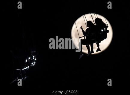 Frankfurt am Main, Deutschland. 10. April 2017. Zwei Frauen sind raste 80 Meter in die Luft mit 60 Kilometer pro Stunde mit dem Mond gesehen hinter ihnen auf der "Jules Verne Turm" Fahrt auf der "Dippemess" folk Festival in Frankfurt am Main, 10. April 2017. Foto: Frank Rumpenhorst/Dpa/Alamy Live News Stockfoto