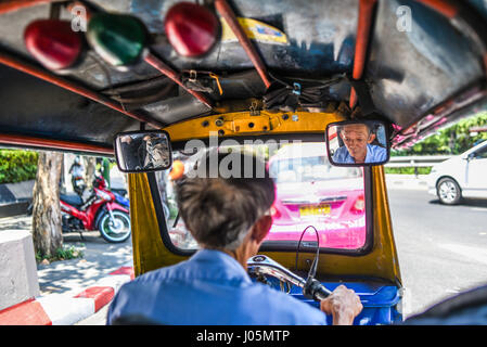 Bangkok, Thailand, 3. März 2016: Tuk Tuk Fahrt durch Bangkok mit Gesicht in alten Treiber innen Autospiegel. Thailand Stockfoto