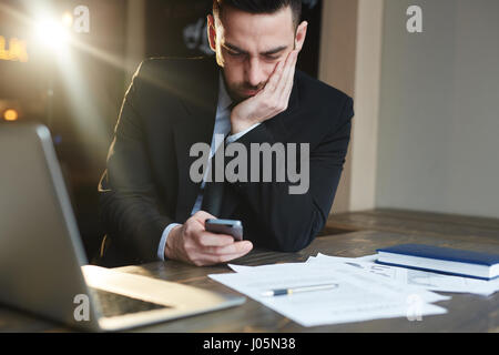 Porträt der moderne Geschäftsmann arbeiten im Büro mit Dokumentation, mit Smartphone Kopf einerseits Ruhe und denken Stockfoto