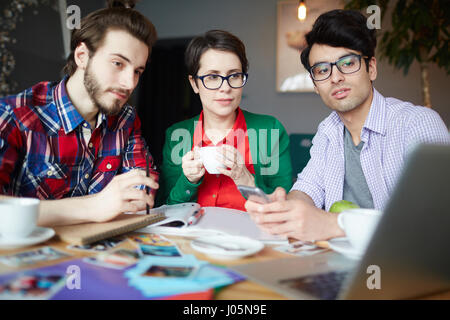 Gruppe von jungen kreativen Menschen arbeiten bei Treffen im Café und Laptopbildschirm sehen Sie Präsentation betrachten Stockfoto