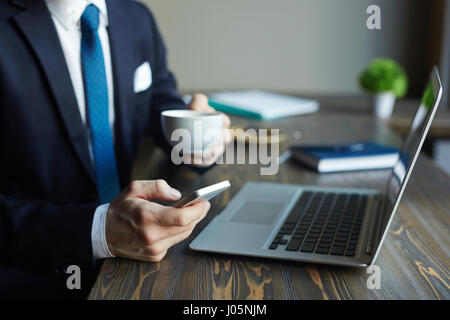 Closeup Portrait unkenntlich elegante Geschäftsmann arbeiten im Café: mit Smartphone und Kaffee trinken Stockfoto