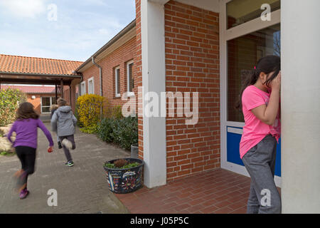 Schülerinnen und Schüler an der Grundschule spielen verstecken und suchen in Pause, Niedersachsen, Deutschland Stockfoto