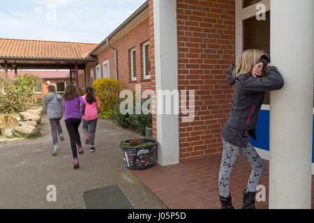 Schülerinnen und Schüler an der Grundschule spielen verstecken und suchen in Pause, Niedersachsen, Deutschland Stockfoto