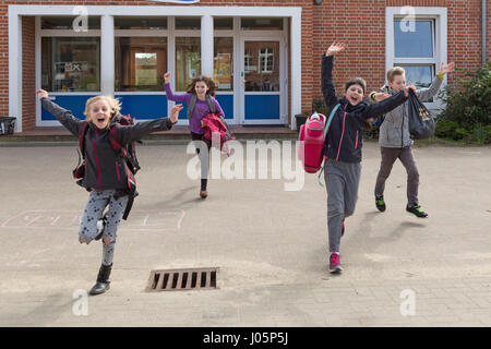 Schülerinnen und Schüler an der Grundschule läuft in ihrem Urlaub glücklich, Niedersachsen, Deutschland Stockfoto