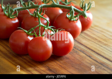 gegen die hellen Blick auf eine Nahaufnahme einer Tomaten-Traube auf einem Holzbrett Stockfoto