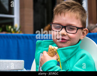 Junge lächelnd Eis essen Kegel mit glücklichen zufriedenen Ausdruck, Schottland, Großbritannien Stockfoto