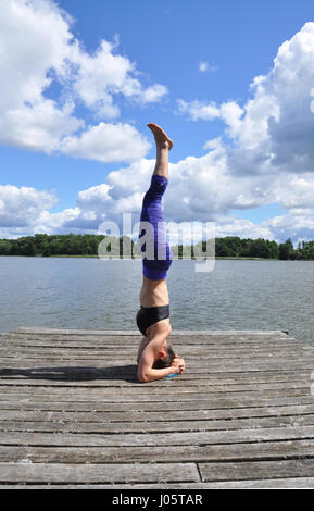 Junge aktive Frau tun Yoga-Positionen auf den Holzsteg am See im polnischen Countsydie in Masuren region Stockfoto