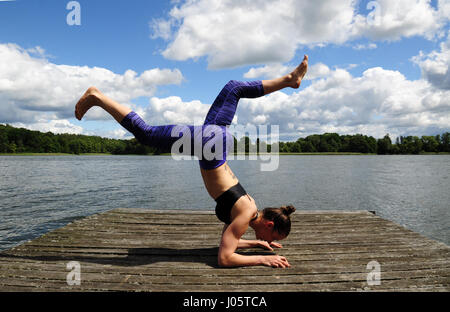 Junge aktive Frau tun Yoga-Positionen auf den Holzsteg am See im polnischen Countsydie in Masuren region Stockfoto