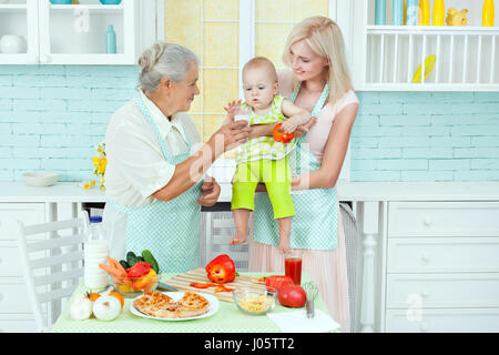 Großmutter und Frau Hausfrau, füttern sie das Baby in der Küche. Stockfoto
