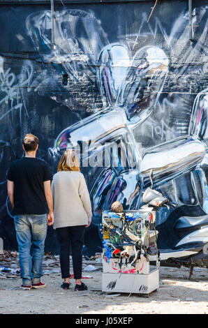 Ein paar stehen und bewundern einige street-Art, eine Wand nach unten eine Gasse direkt an der Brick Lane im East London, UK Stockfoto