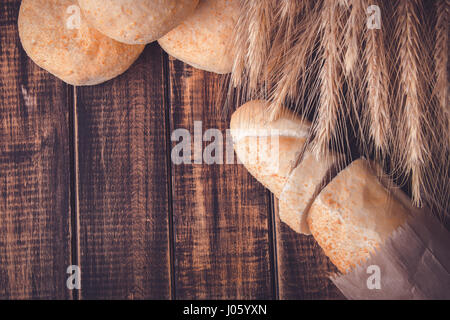 Verschiedene Arten von frisch gebackenem Brot auf einem rustikalen Holztisch in der Nähe von Weizen. Gesunde Ernährung-Konzept. Textfreiraum Stockfoto