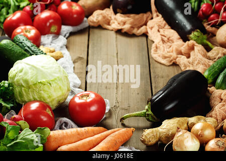 Rahmen aus frischem Gemüse auf rustikalen Holztisch. Ansicht von oben Platz für Text. Auberginen, Kohl, Karotten, Tomaten, Zwiebeln und anderen. Stockfoto