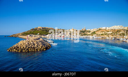 Gozo, Malta - der alte Hafen von Mgarr mit Leuchtturm auf der Insel Gozo an einem hellen sonnigen Sommertag mit blauen Meerwasser und klarem Himmel Stockfoto