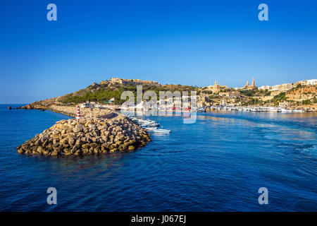 Gozo, Malta - der alte Hafen von Mgarr mit Leuchtturm auf der Insel Gozo an einem hellen sonnigen Sommertag mit blauen Meerwasser und klarem Himmel Stockfoto